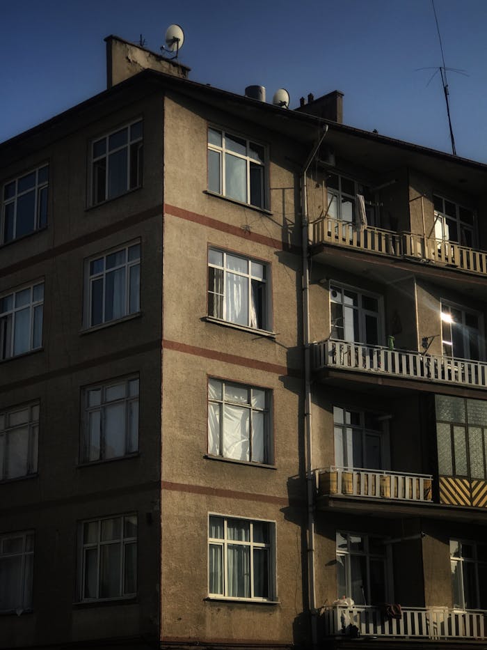 Low-angle view of an urban residential building facade with balconies at sunset.